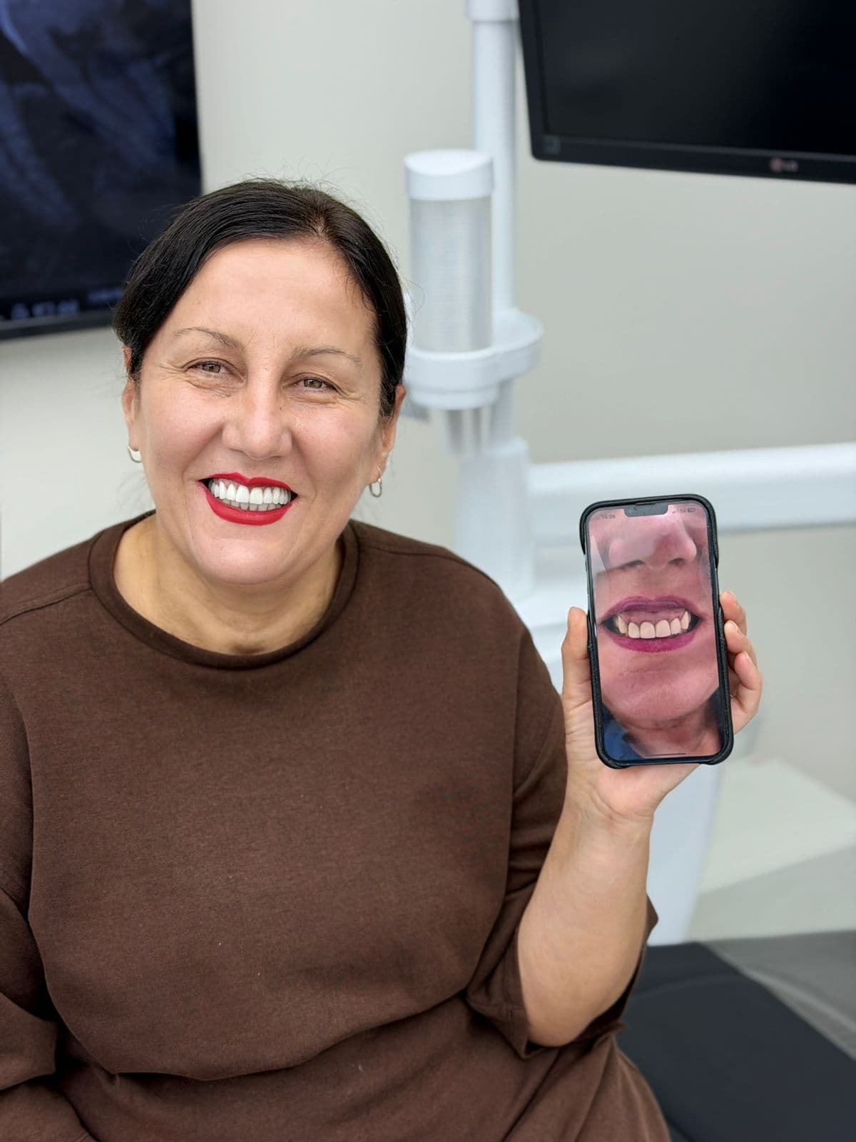 Una paziente sorridente mostra una foto del suo sorriso precedente